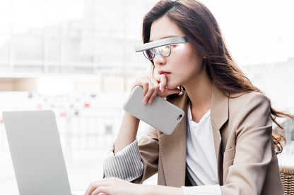 Vrouw draagt lichttherapie-bril boven haar gewone- of leesbril tijdens werk op laptop